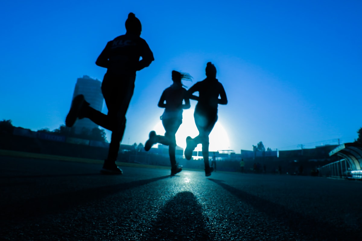Silhouette of three women running together at sunset
